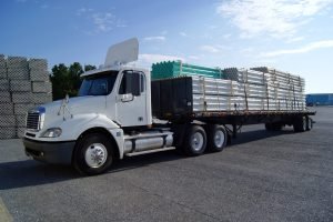 white-flatbed-Truck-Loaded-with-pipes-scaled